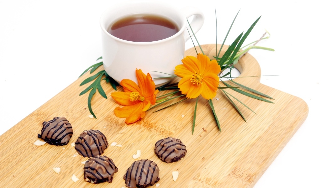 Чашка чая на деревянной доске с конфетами