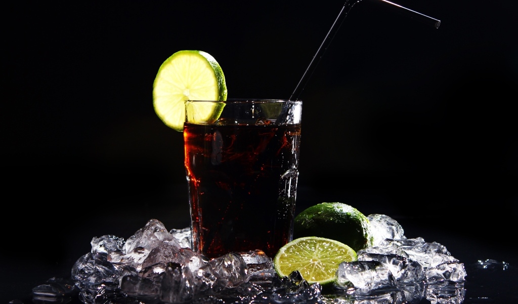 Стакан колы со льдом на черном фоне с кусочками лимона