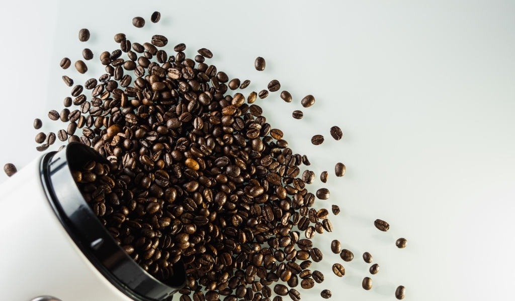 Много кофейных зерен на сером столе