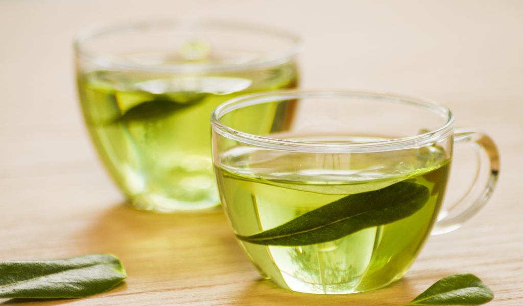 Две чашки зеленого чая с листьями