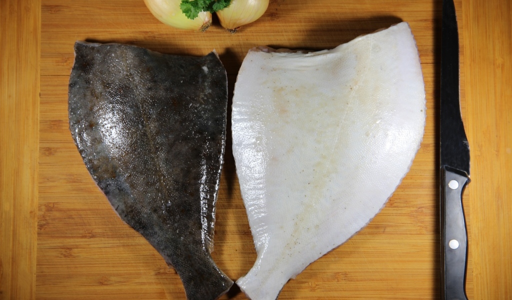 Камбала на доске с луком и ножом