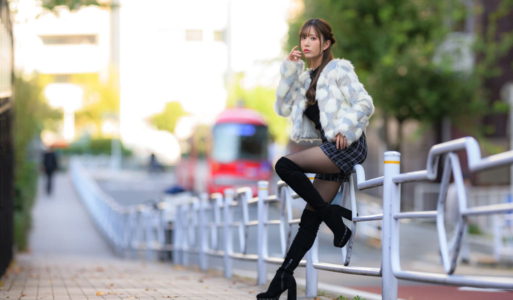 Азиатка в шубе стоит у забора