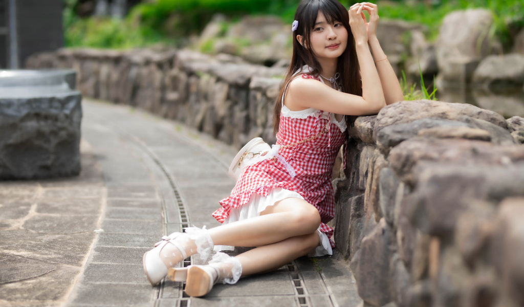 Азиатка сидит на земле в красном платье