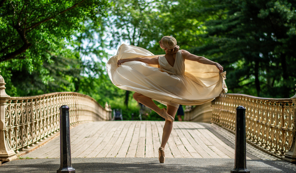 Девушка балерина в стойке на мосту