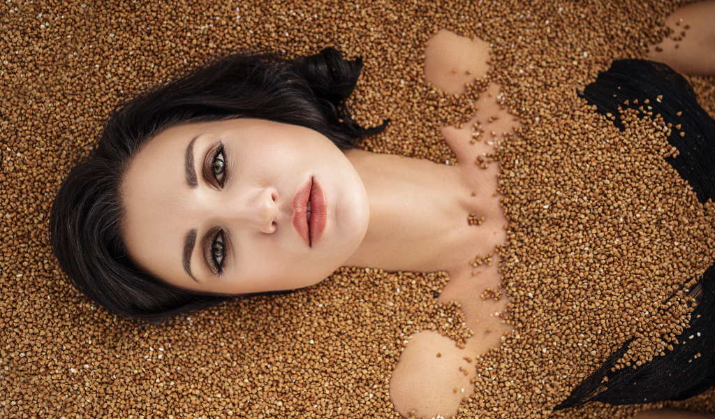 Красивая девушка лежит в зернах гречки