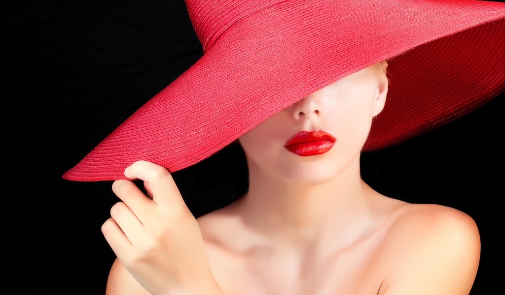 Девушка в большой красной шляпе на черном фоне