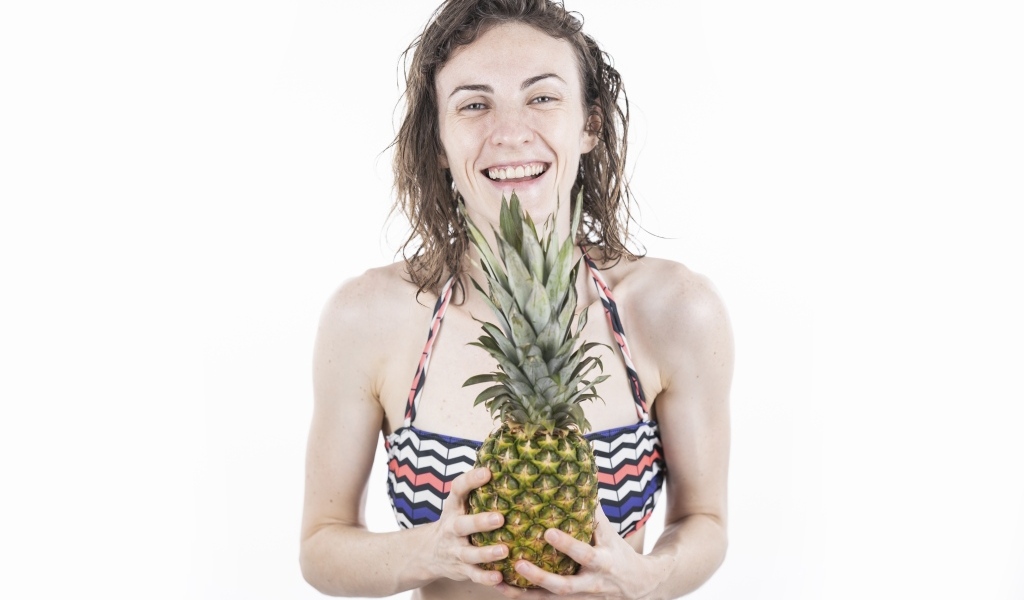 Улыбающаяся девушка с ананасом в руках