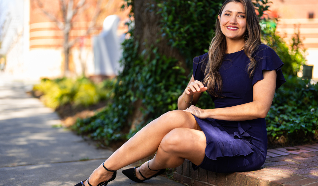 Улыбающаяся женщина в синем платье сидит на земле