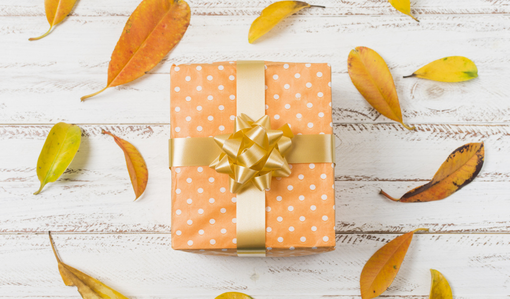 Подарок с желтыми листьями на белом фоне