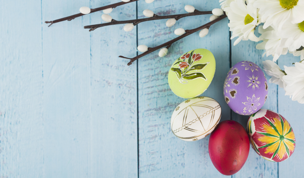 Красивые пасхальные яйца с ветками вербы и цветами хризантемы на голубом фоне