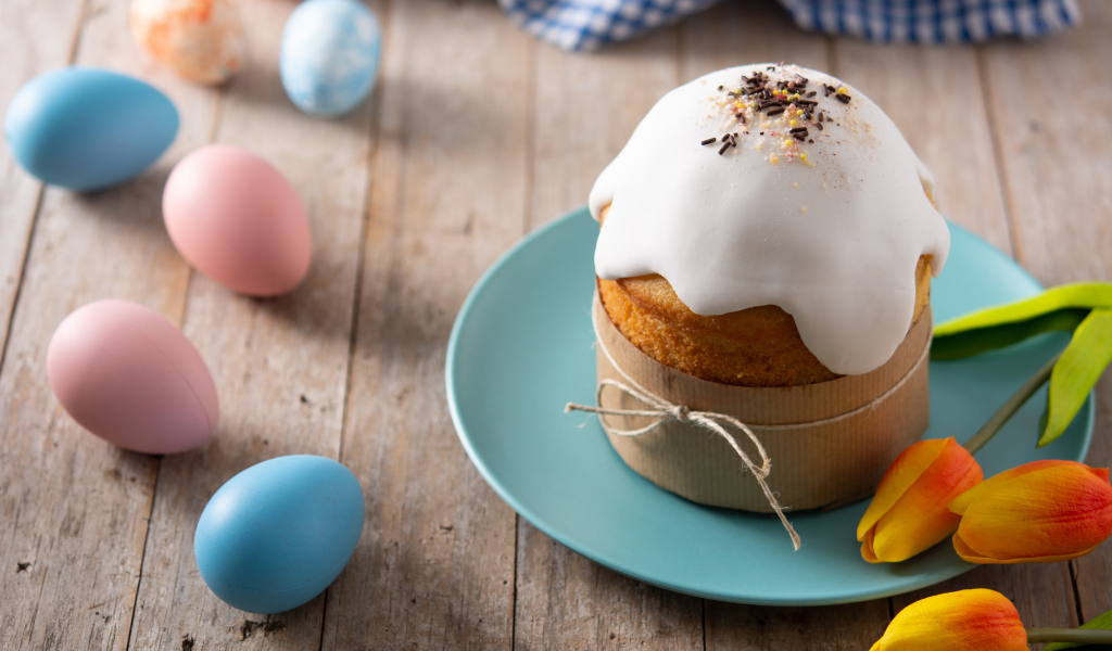 Кулич с крашеными яйцами и цветами на столе на Пасху