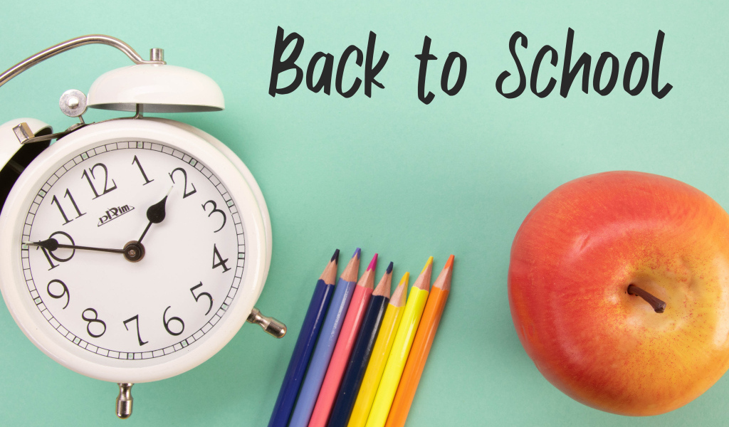 Будильник, карандаши и яблоко на фоне с надписью пора в школу