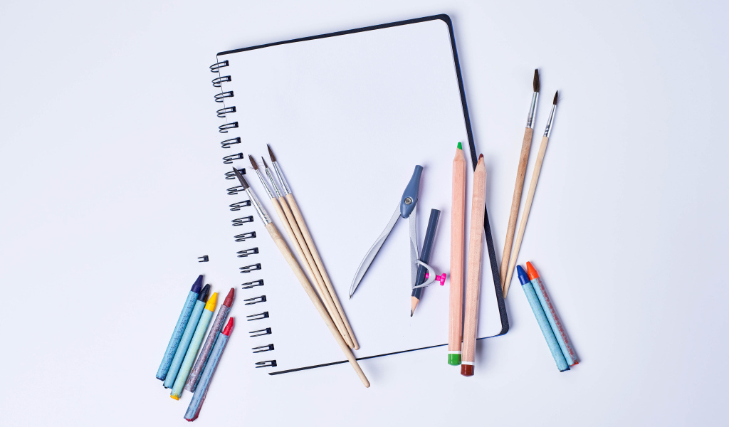 Карандаши, кисти и блокнот для рисования на сером фоне