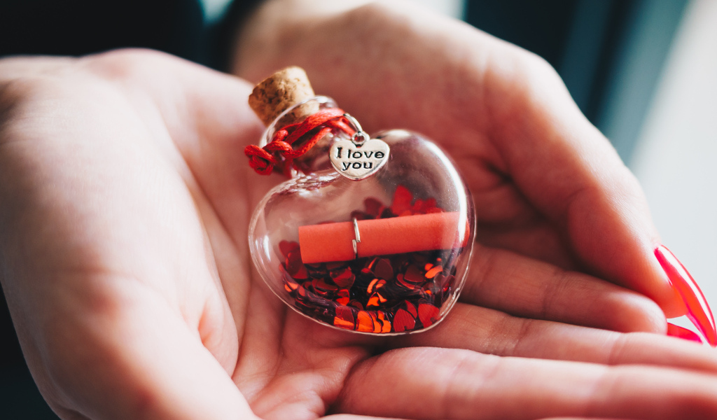 Ладони с маленький стеклянным сердечком