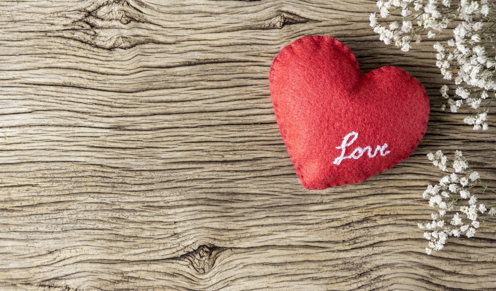 Красное тканевое сердце с цветами на деревянном столе