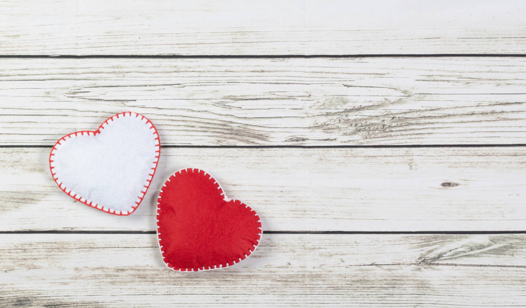 Белое и красное сшитое сердце на деревянном фоне
