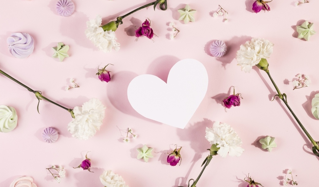 Белое бумажное сердце на розовом фоне с цветами