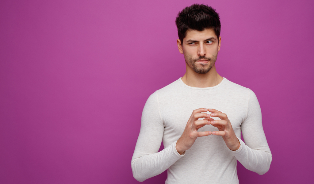 Хитрый мужчина в белом свитере на сиреневом фоне