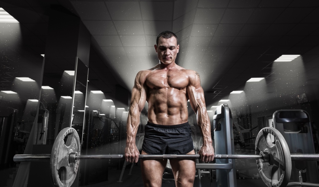 Сильный мужчина качает штангу в спортзале