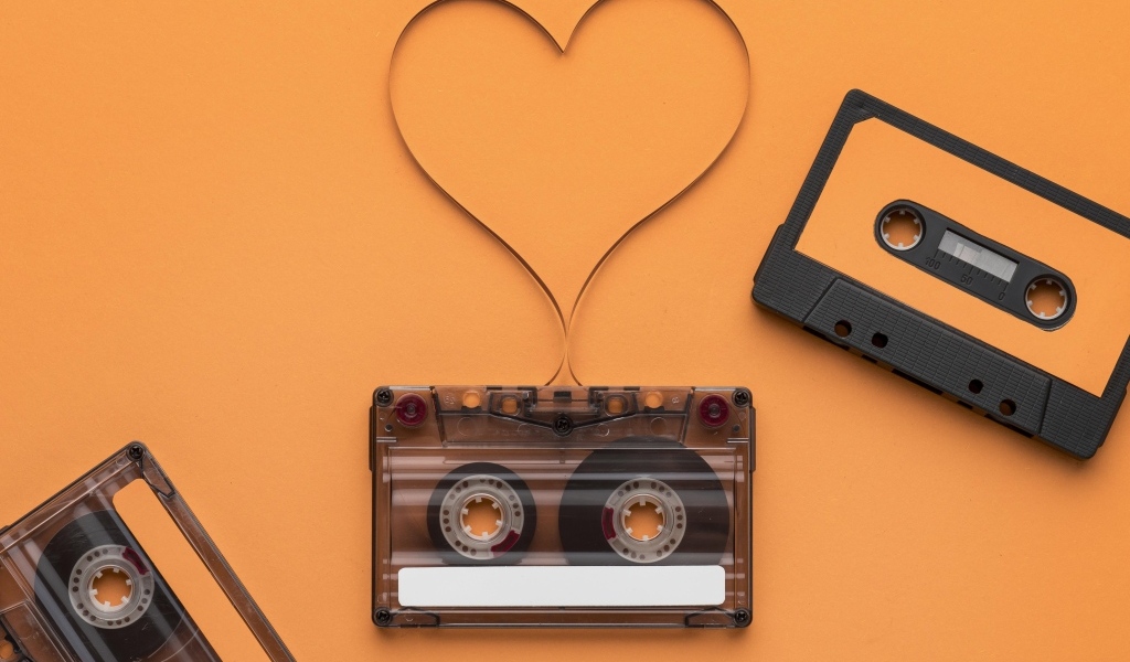 Кассеты и сердце из ленты на оранжевом фоне
