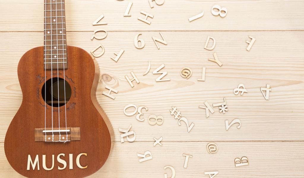 Гитара с буквами на деревянном фоне