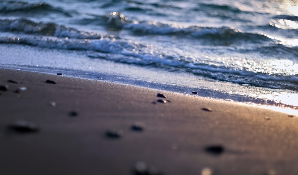 Мокрый морской песок омывает вода