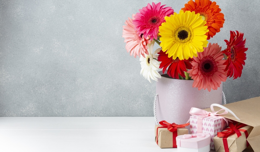 Букет разноцветных цветов герберы на столе с подарками