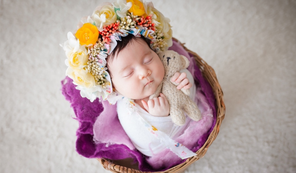 Младенец с венком на голове спит в корзине