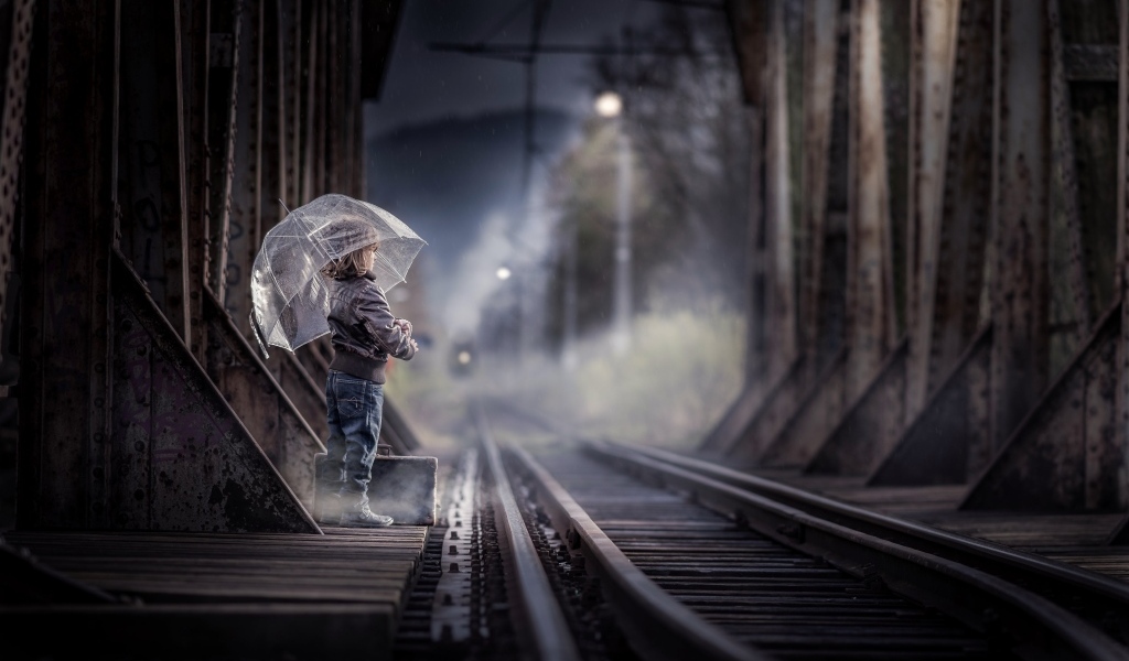 Ребенок под зонтом у железной дороги