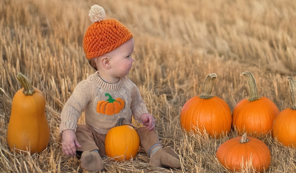 Маленький ребенок сидит на поле с тыквами