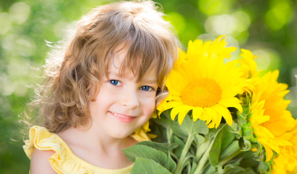 Красивая голубоглазая девочка с букетом подсолнухов