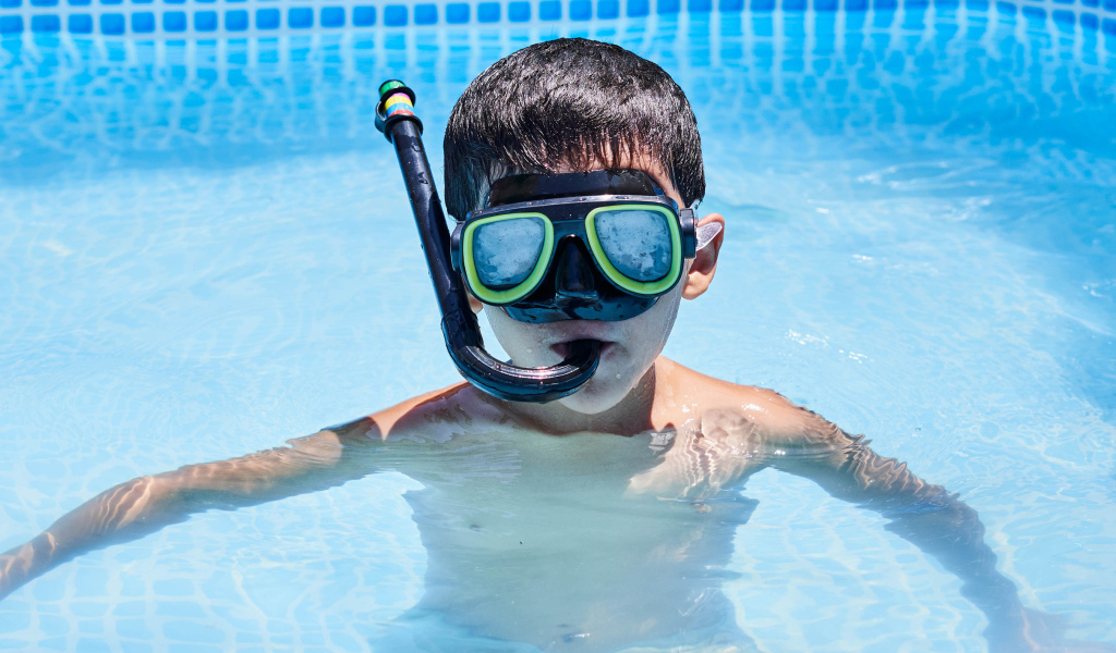 Мальчик в маске сидит в плавательном бассейне