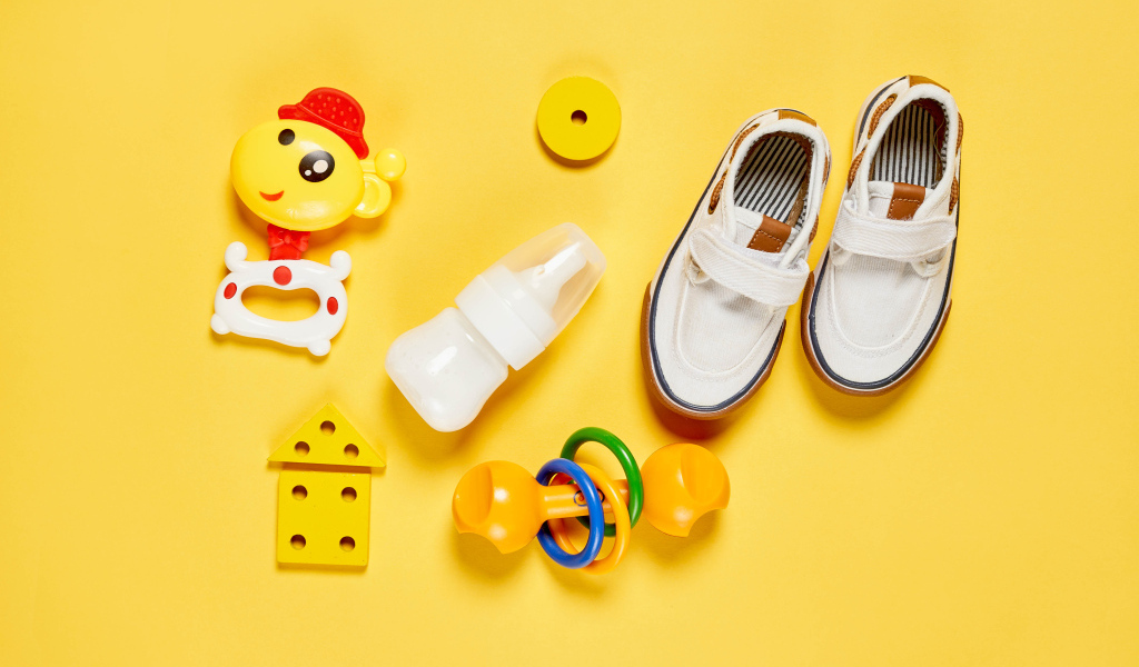 Детские игрушки и обувь на желтом фоне
