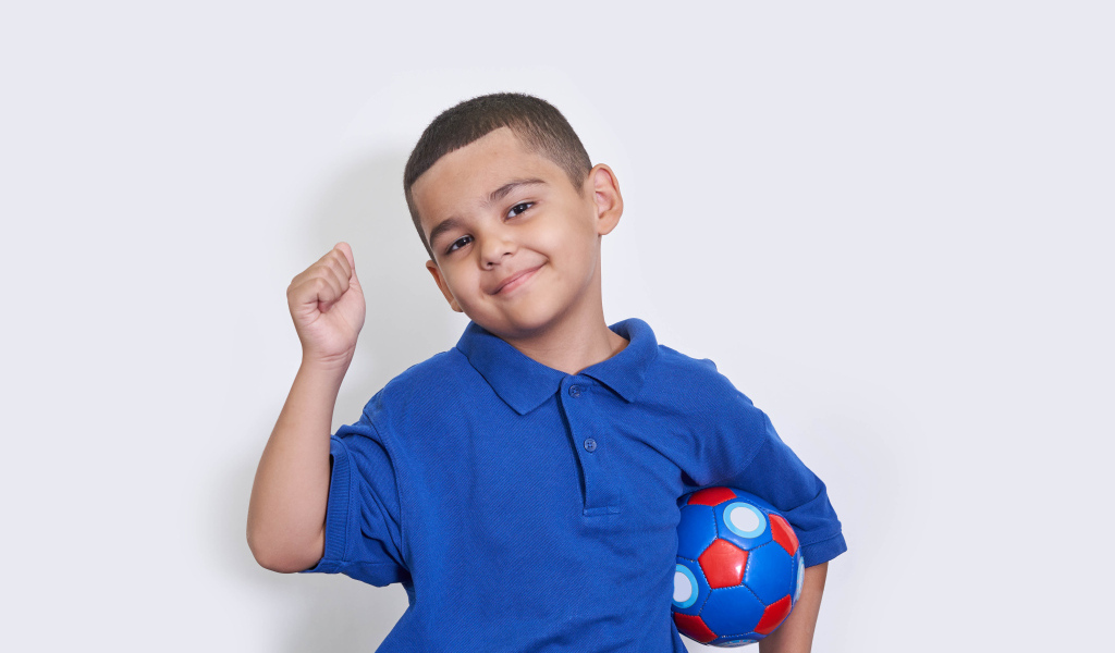 Милый мальчик с мячом на белом фоне