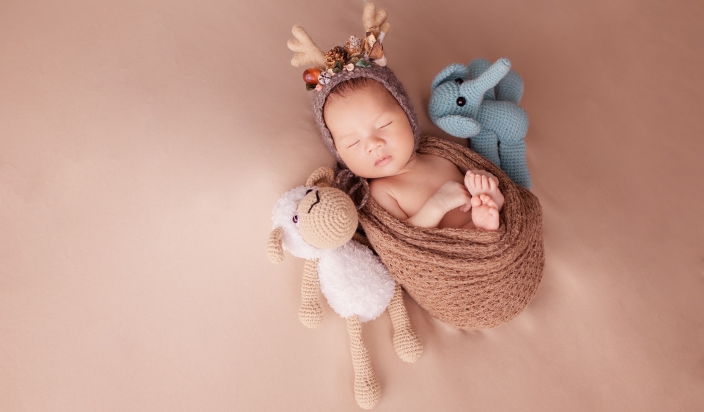 Маленький ребенок в костюме оленя с игрушкой