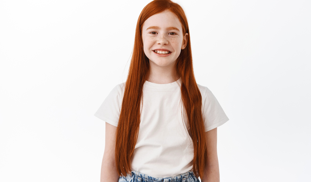 Улыбающаяся рыжеволосая девочка на белом фоне