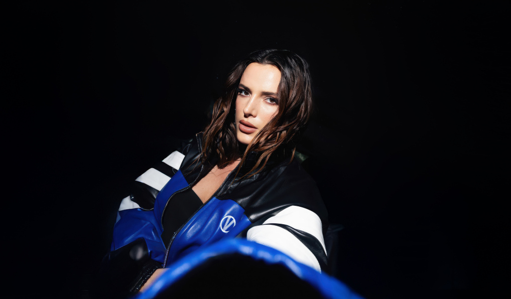 Актриса Белла Торн в кожаной куртке на черном фоне