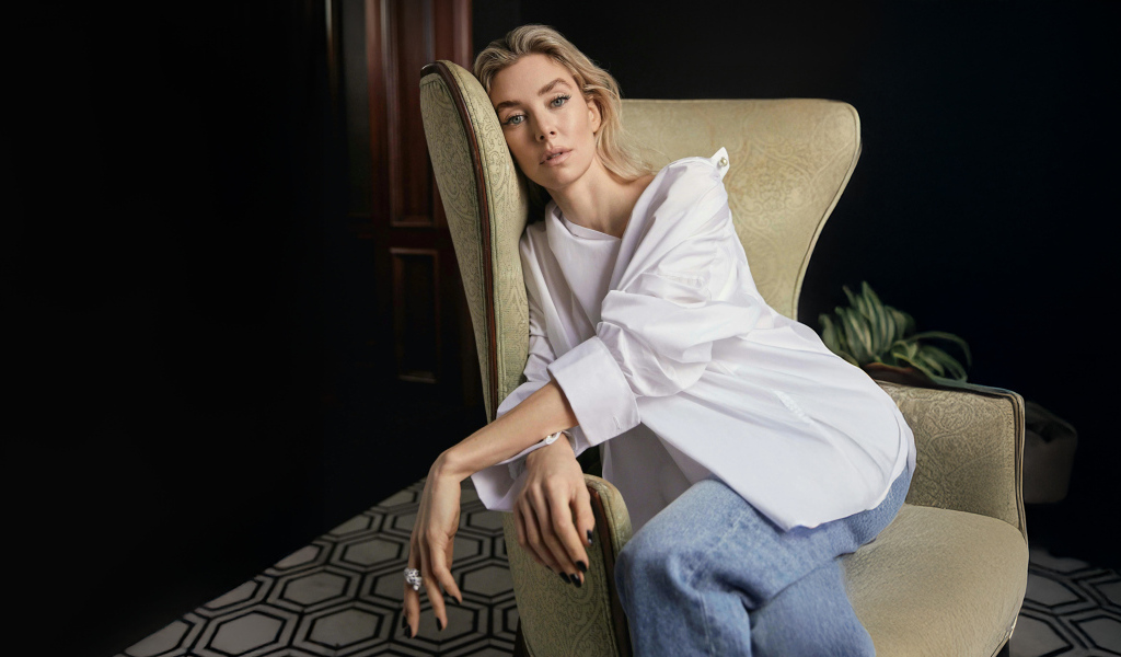 Актриса Ванесса Кирби в белой рубашке сидит на кресле