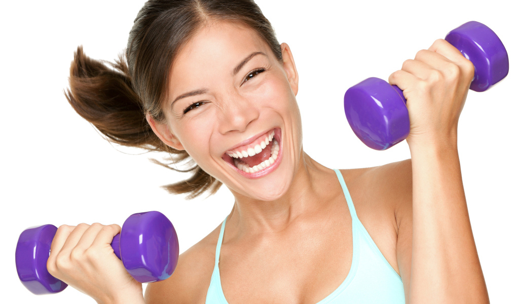 Веселая спортивная девушка с гантелями в руках