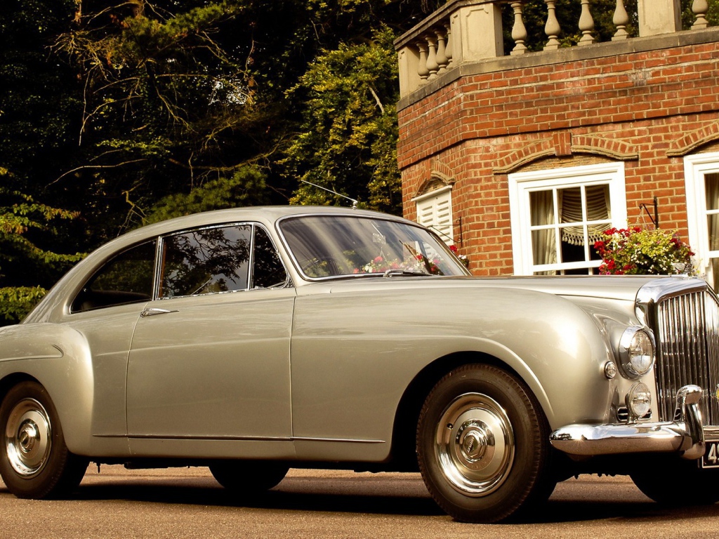 Белый автомобиль у кирпичного дома