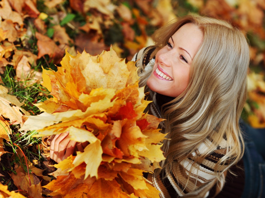 Красивая девушка держит осенние листья
