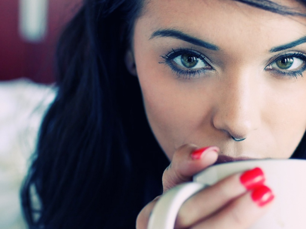 Девушка брюнетка с пирсингом в носу и красными ногтями