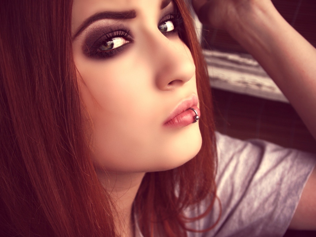 Молодая девушка шатенка с пирсингом в губе