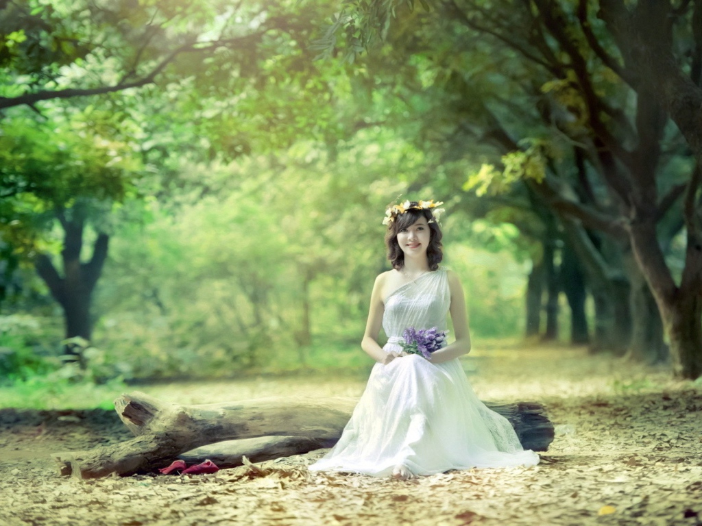 Девушка сидит на бревне