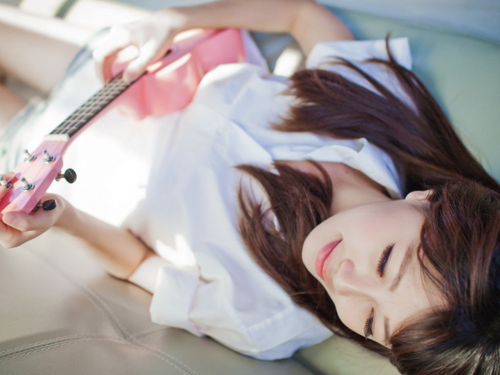 Брюнетка и розовая гитара на диване