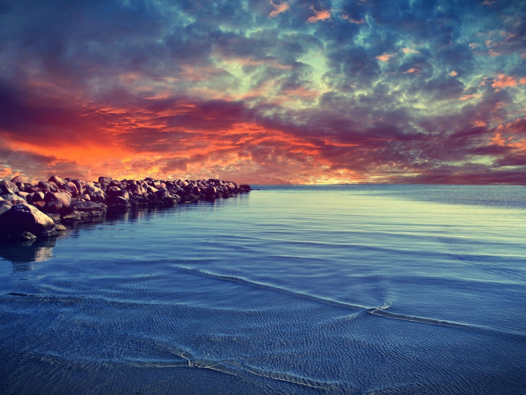 Красный закат над каменистым берегом