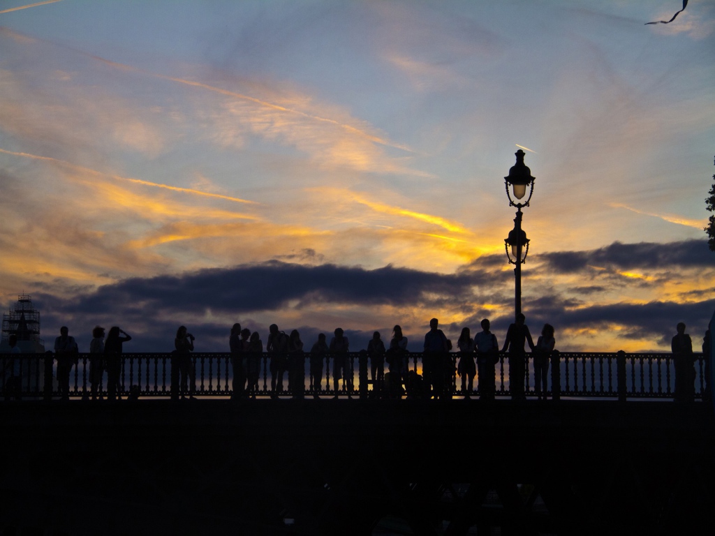 Люди провожают солнце на мосту