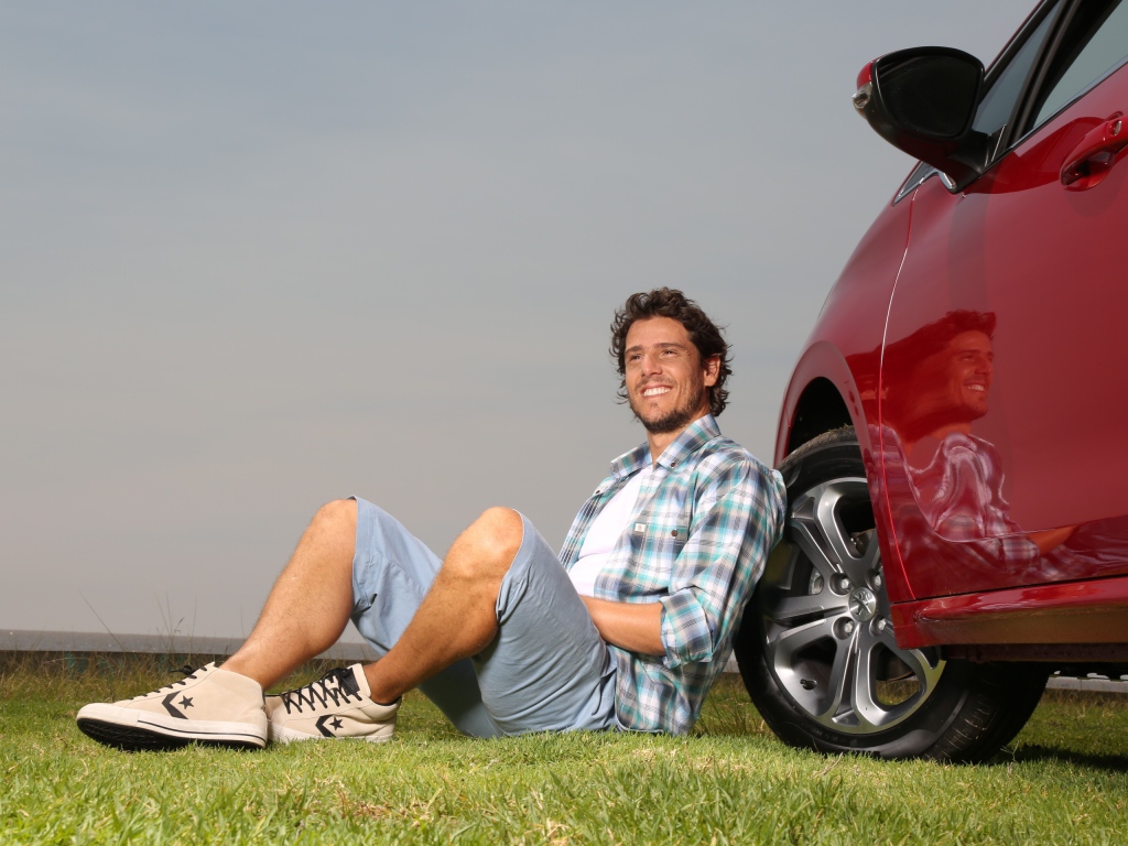 Мужчина сидит у колеса своего автомобиля