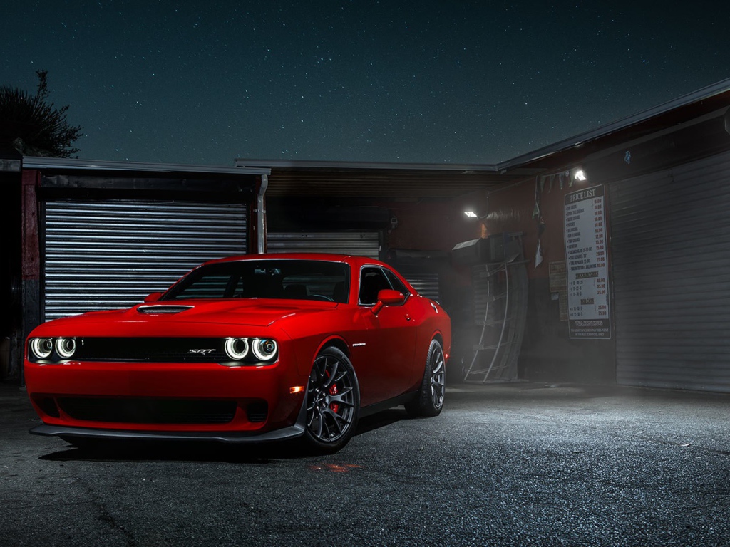Красный Dodge Challenger Hellcat у гаража
