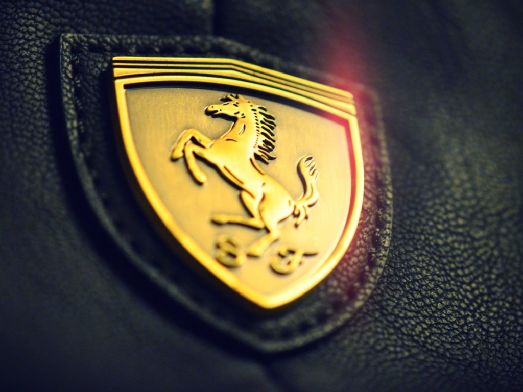 Золотой символ Ferrari на черной коже